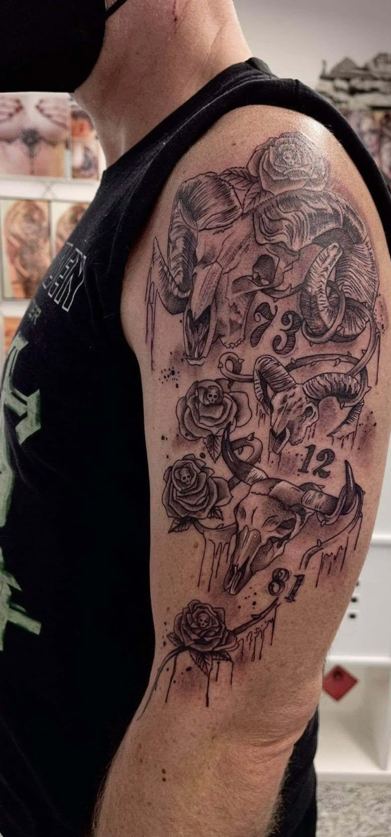 Person mit schwarzem ärmellosen Shirt zeigt ein detailliertes Tattoo auf dem Oberarm.